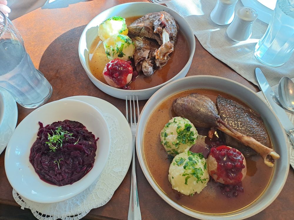 Martinigansl mit Knödel und Blaukraut.
Es stehen 2 Teller nebeneinander und 1 Portion Blaukraut in einem Schüsserl daneben.