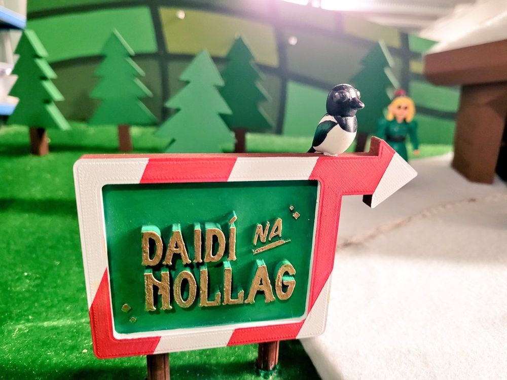 A sign with a magpie sitting on it. Text reads "Daidí na Nollaig"