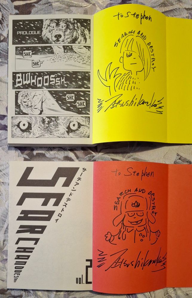 Copies of Search and Destroy volumes one and two with signatures and remarks by creator Atsushi Kaneko - Hyaku in volume 1 (yellow, top) and Doro in volume 2 (red, bottom).