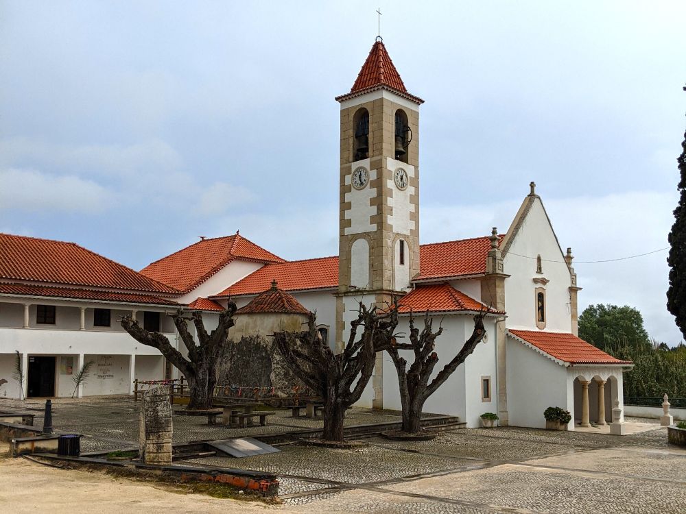A photograph of a Christian church, with a prehistoric dolmen on the side serving as a chapel