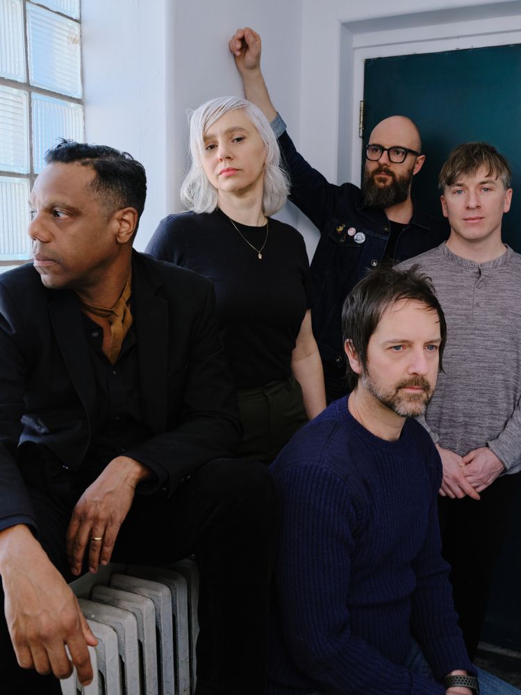 A portrait of rock band The Dears in a hallway setting. From Left to right we see Murray Lightburn, Natalia Yanchak, Steve Raegele (in front), Jeff Luciani, Remi-Jean LeBlanc.