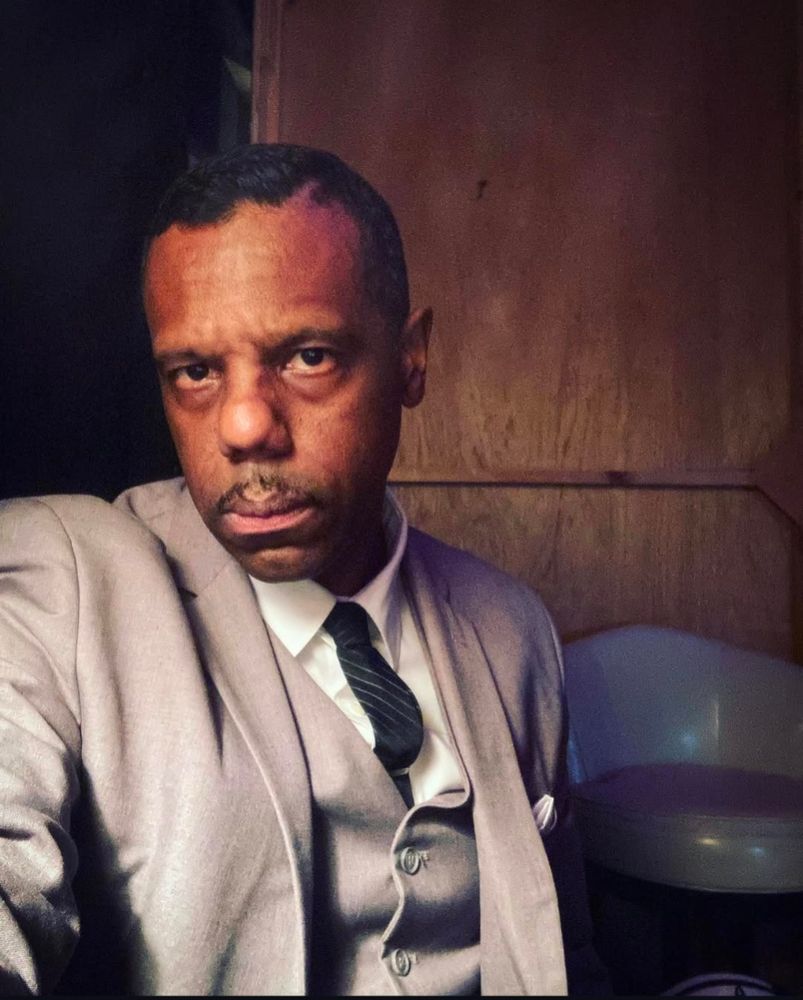 A portrait of singer Murray Lightburn wearing a 3 piece light grey suit.