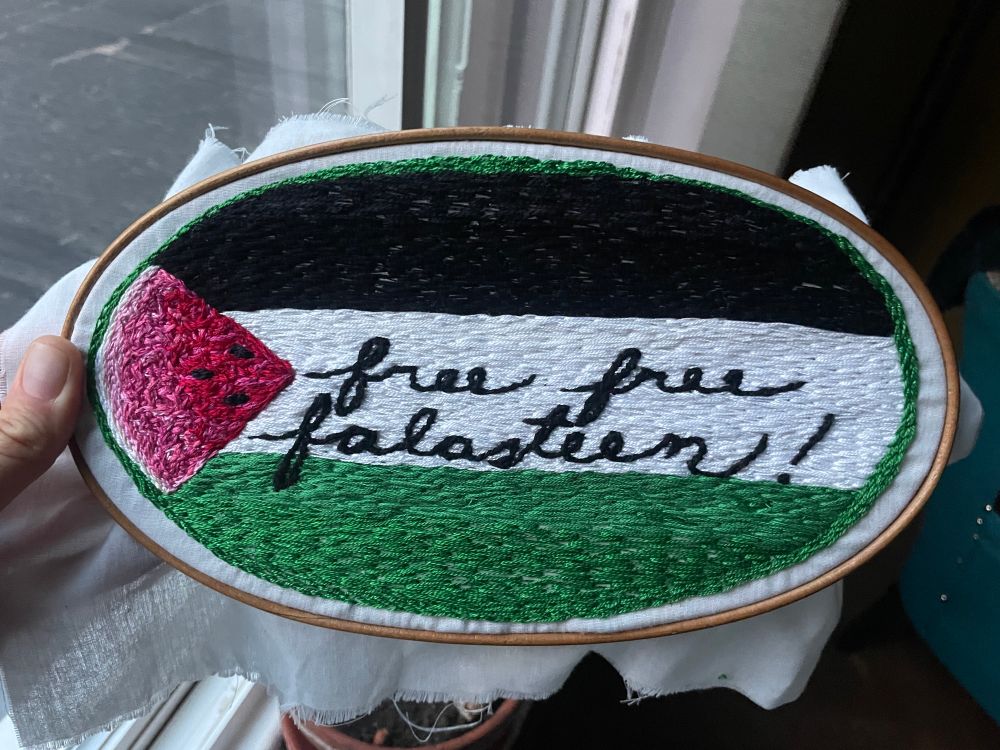 “free free falasteen” embroidered over Palestinian flag. The red triangle is a slice of watermelon.