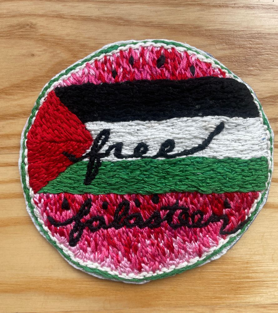 “free falasteen” embroidered over Palestinian flag. The remainder of the circle patch is embroidered like the inside of a watermelon.