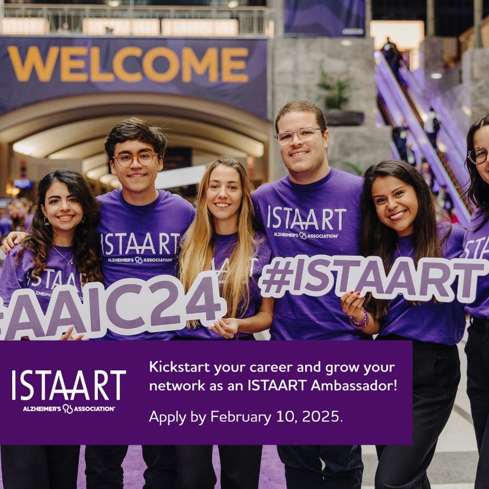 A group of international early career researchers wearing purple tee shirts and holding cut out signs reading “AAIC” and “ISTAART”