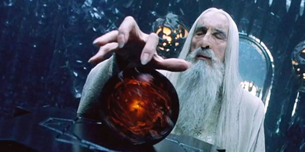 A screenshot of the evil wizard Saruman from Lord of the Rings places his hand over the seeing stone (known as Palantir) and closes his eyes to spy on his enemies.