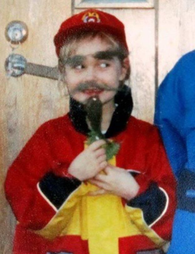 a photo of yours truly at maybe 7 years old donning a beard, moustache and eyebrows made of ”beard moss” off of a spruce, with a mischievous face looking towards my brother off to the side out of frame.