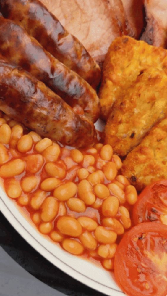 a close up of a plate of food with beans and sausages