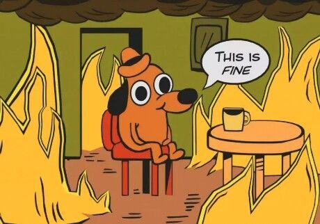 "This is fine" meme. A cartoon dog sits upon a stool in the middle of a burning room with the caption "This is fine". There is a table and a mug to the right of him. Presumably his beverage is not cold given the rising ambient temperature of the room. Perhaps the mug is empty? We do not know.
