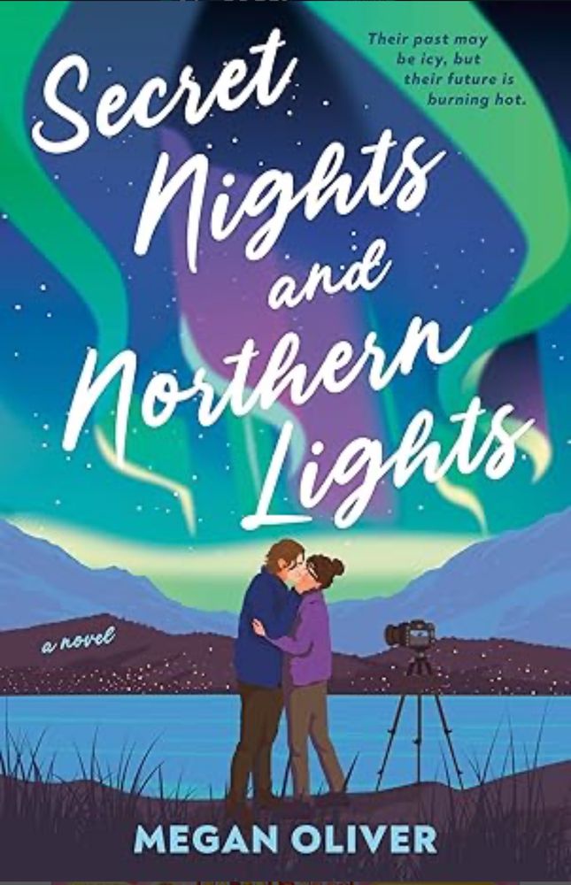 Illustrated book cover for SECRET NIGHTS AND NORTHERN LIGHTS by Megan Oliver. A man and woman in warm clothes embrace in the foreground with a lake, mountain range, and aurora borealis in the background. A camera on a tripod is to their right. 