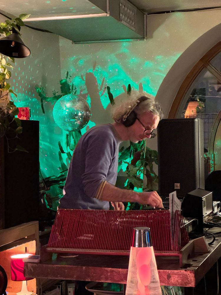 DJ at the turntables in warmly lit vinyl music bar. 