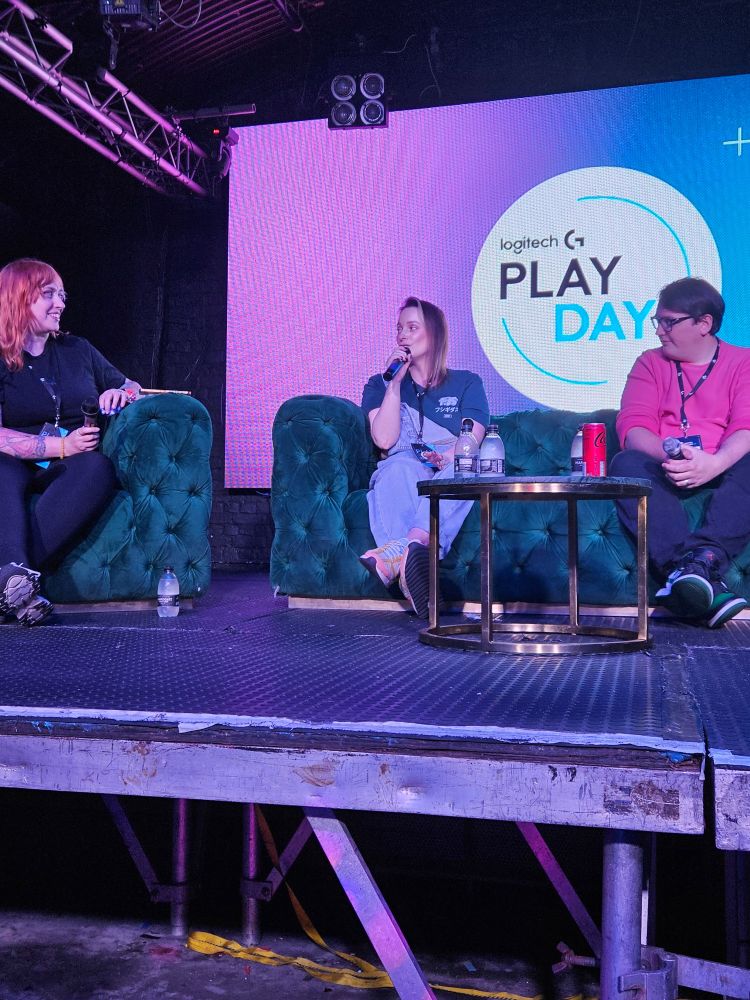 Three people sat on sofas on the stage for a panel.
