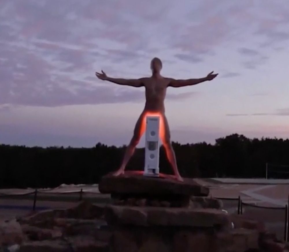 Nakedman in top of a mound of rocks standing in front of a red light.