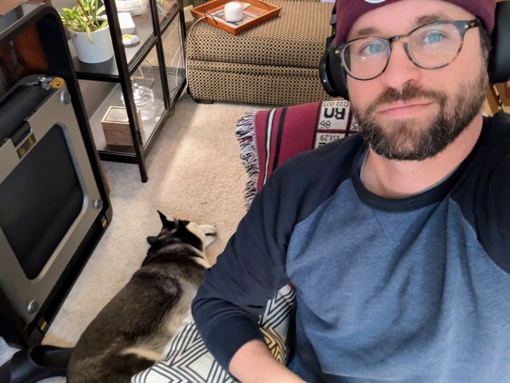 Man in sweater and cap with glasses and husky snoozing peacefully on the floor 