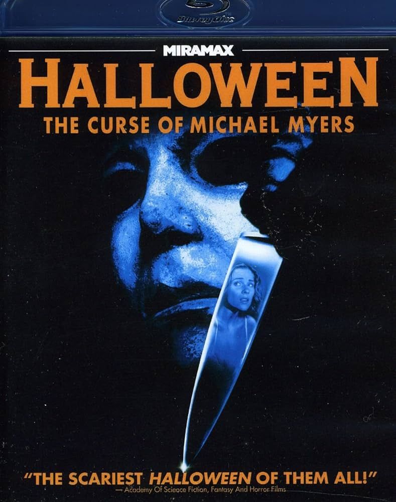 The cover of Halloween: The Curse of Michael Myers, with a close up of MIchael Myers Mask holding a knife with a woman in the reflection of the knife