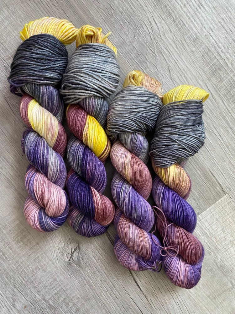 Four twisted skeins of grey, purple and yellow yarn