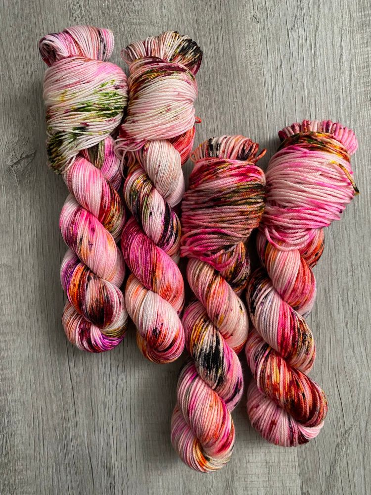 Four skeins of red, pink and black speckle yarn.