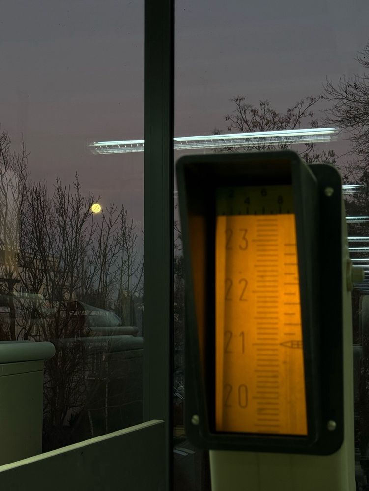 The analog interface of a paper guillotine with the full moon in the sky in the background 