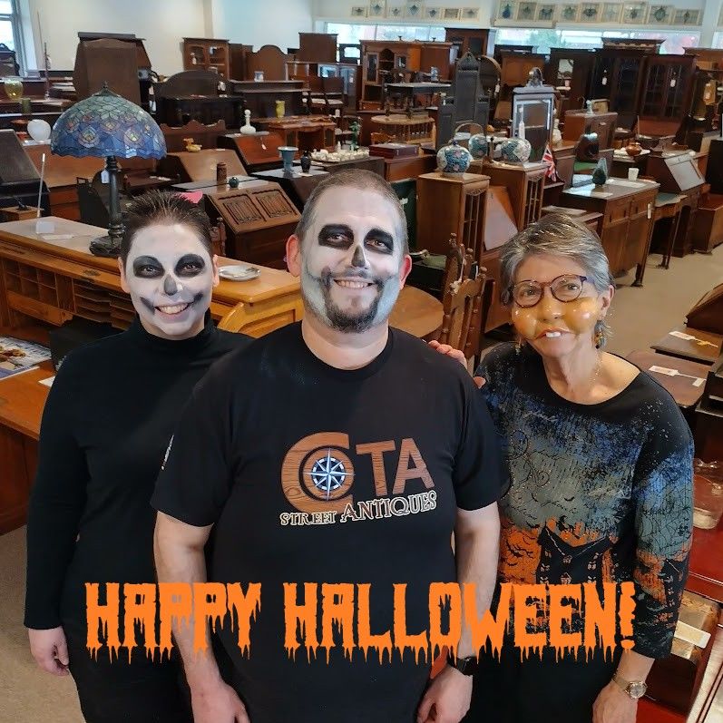 The owners/employees of Cota Street Antiques pose in the furniture store wearing Halloween makeup/masks.