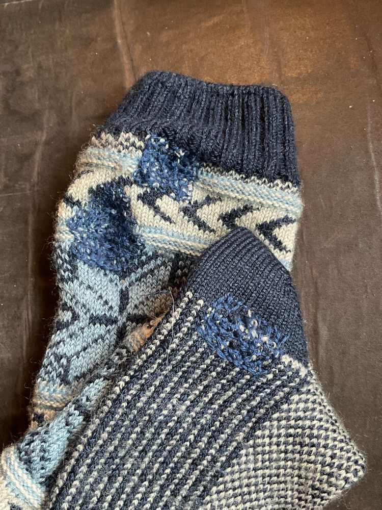 Two navy and white socks with Scottish Darning patches in blue. 