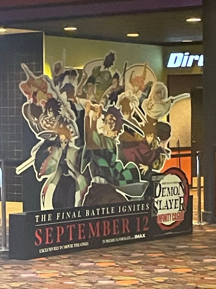 Cardboard cutout of the demon slayer movie standing in a movie theater