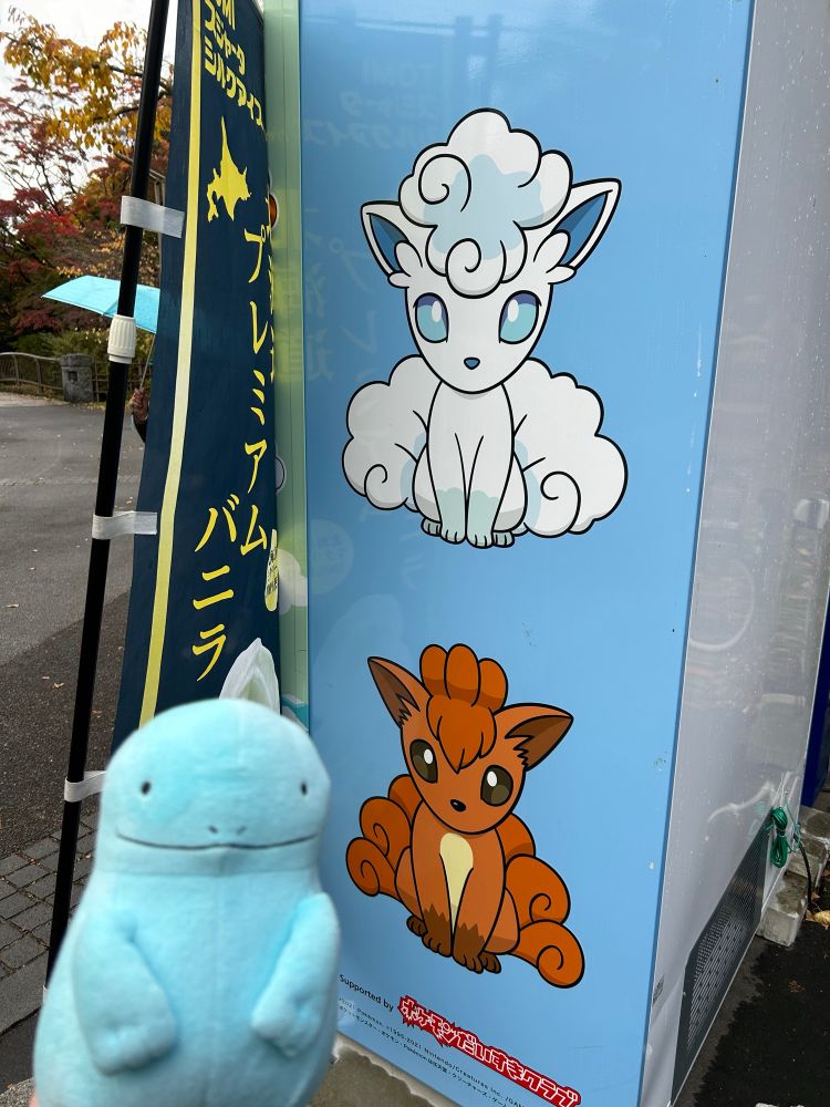 ロコンとロコン(アローラのすがた)が描かれた自動販売機とヌオーのぬいぐるみの写真。ポケモンに会えるとは思いもよらず、驚きが隠せない。