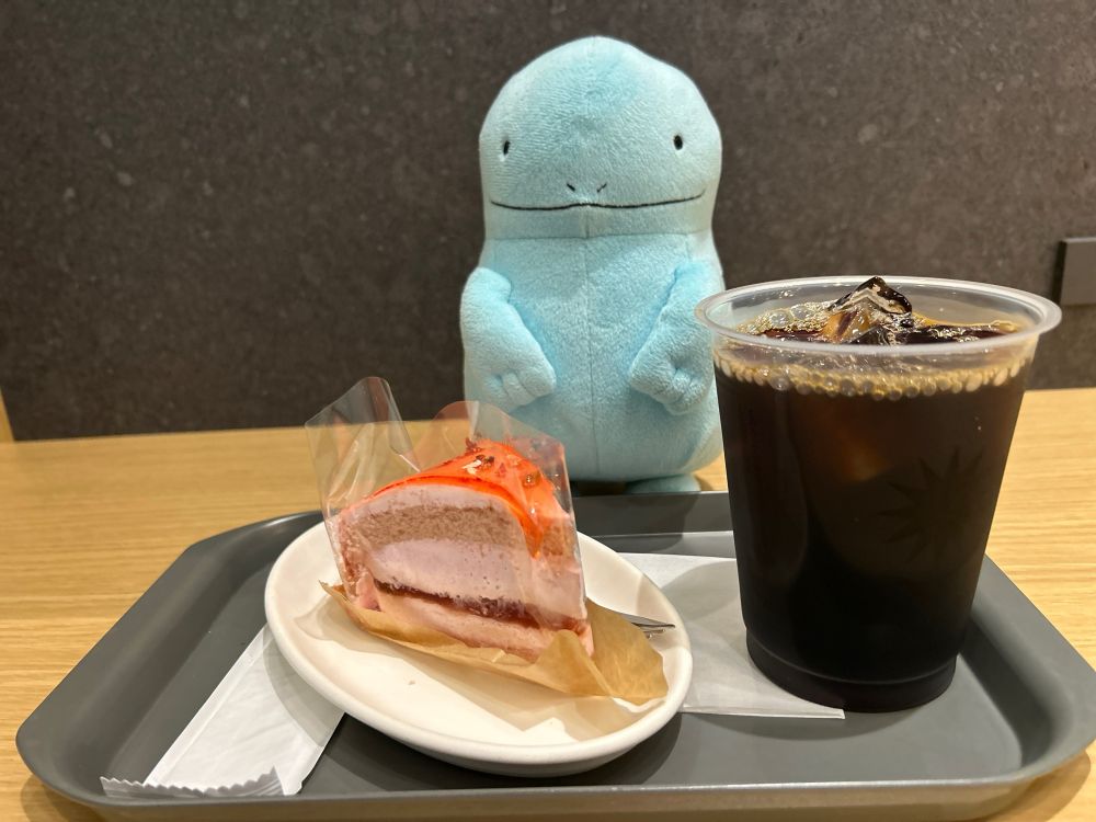 PRONTOのストロベリームースケーキとアイスコーヒーの写真。奥にいるヌオーの目はどこに向いているのか。