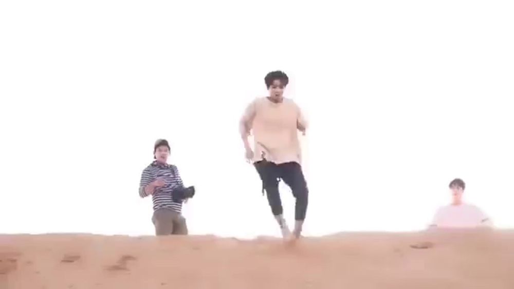 a person is laying on top of a sand dune in the desert .