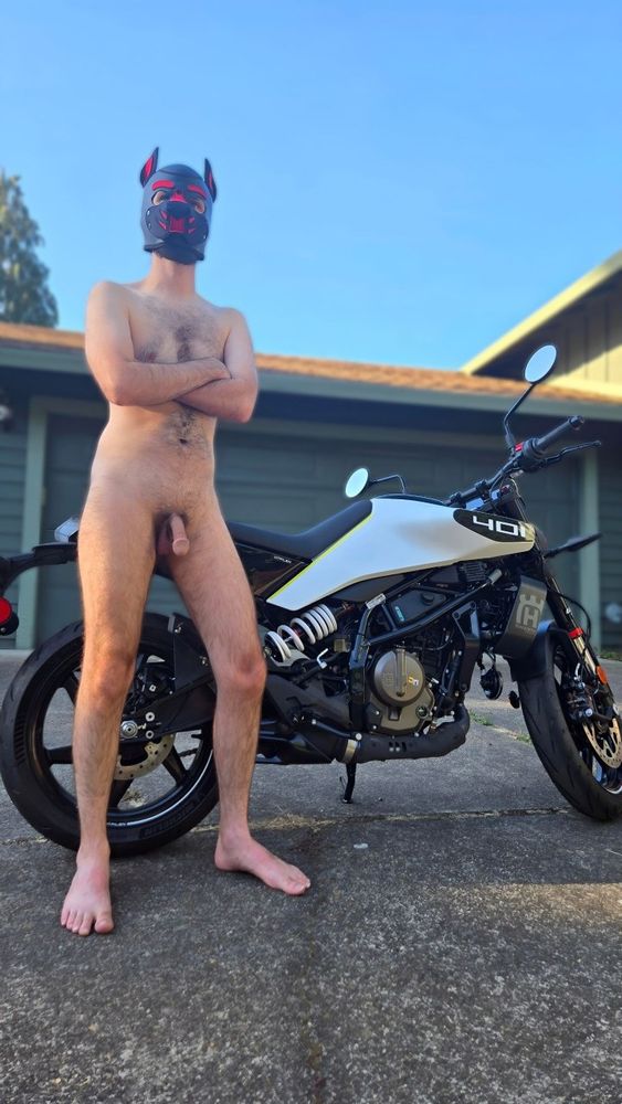 I'm standing to the side of my white motorcycle while naked and in my puphood. Low angle