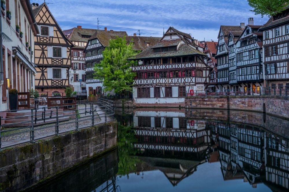 A still canal reflects black and white timber framed houses Alsace is famed for having.