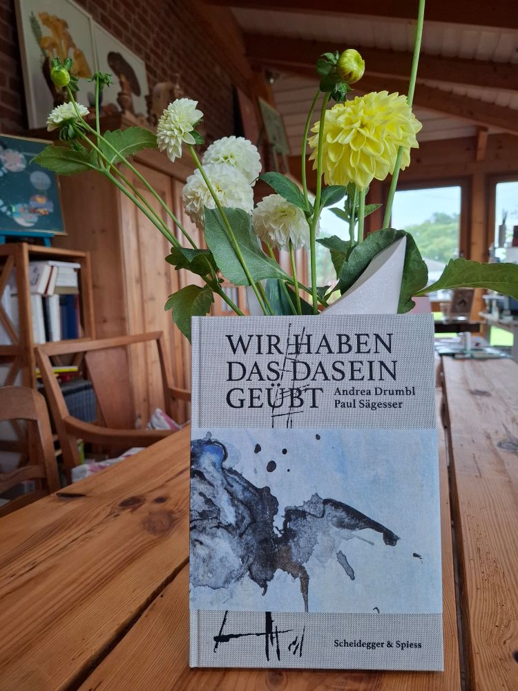 Das Buch, gelehnt an eine Vase mit Dahlien.