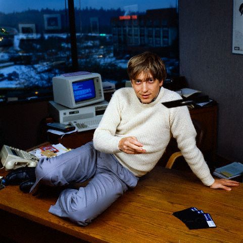 Young bill gates tossing a floppy disk while sitting on his office desk