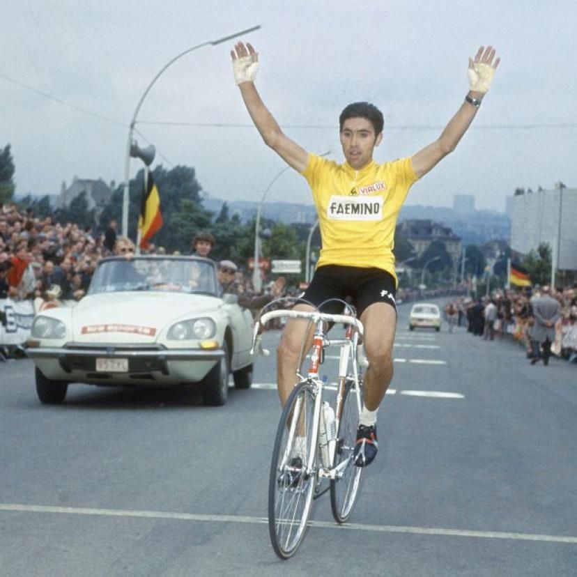 Eddy Merckx crossing the finish line on Tour of Brussels wearing a yellow jersey and riding a white road bike.