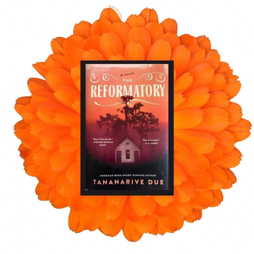 Cover of The Reformatory by Tanarive Due on top of an oversized bright orange gerber daisy on a white background. 
