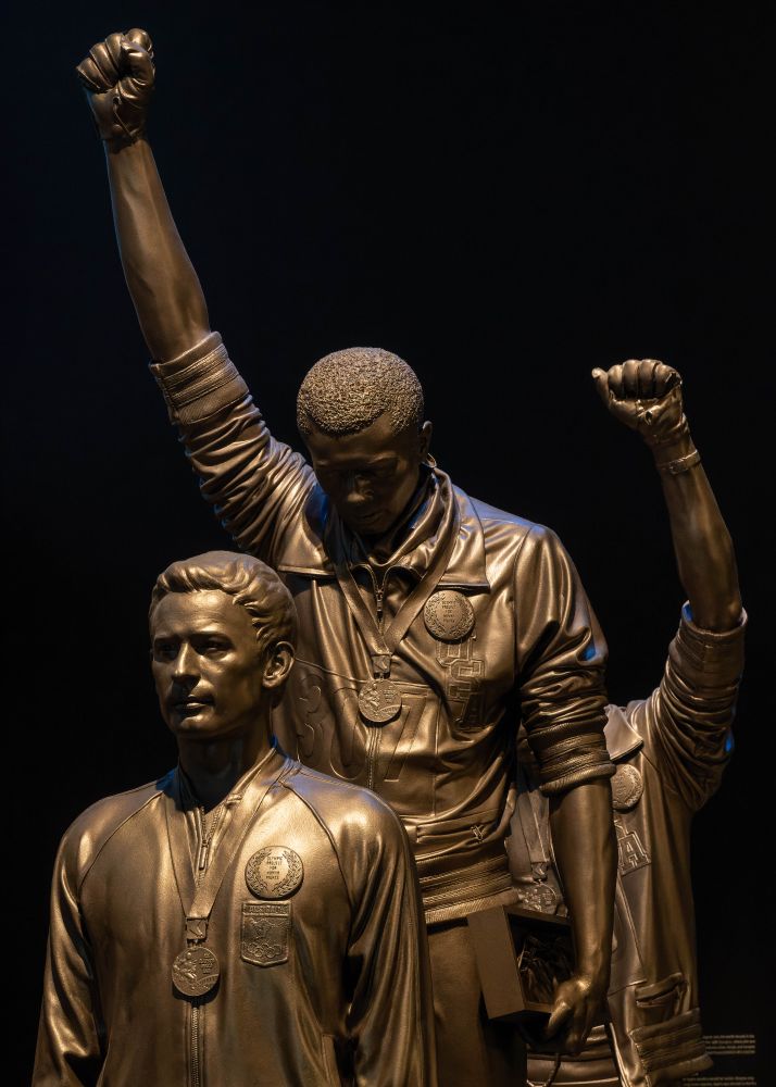 Statue of Tommie Smith and Juan Carlos on the podium at the 1968 Olympic Games, gloved fists raise in silent protest. 