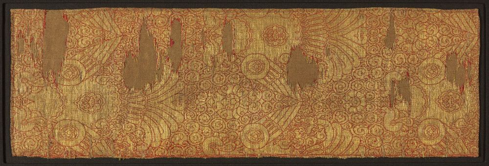 Gold fabric with frond-like pattern on a background of slight red (typical of Chinese cloth of gold) -- some areas are missing due to age.