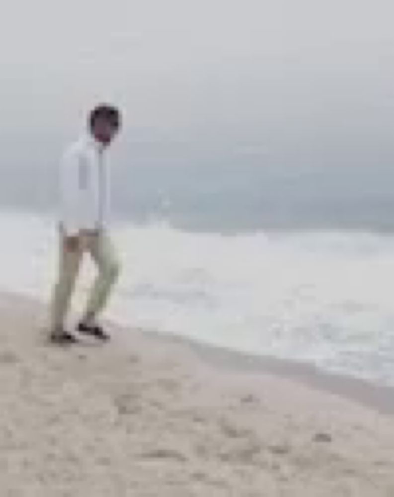 a man is standing on a beach near the ocean