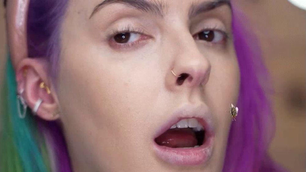 a woman with purple hair has a nose ring