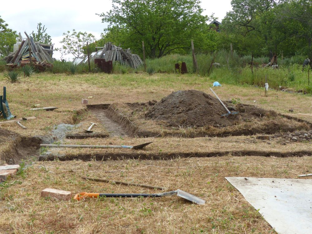 An area is marked out on the ground and then the dirt is removed to make trenches where the concrete foundations will go