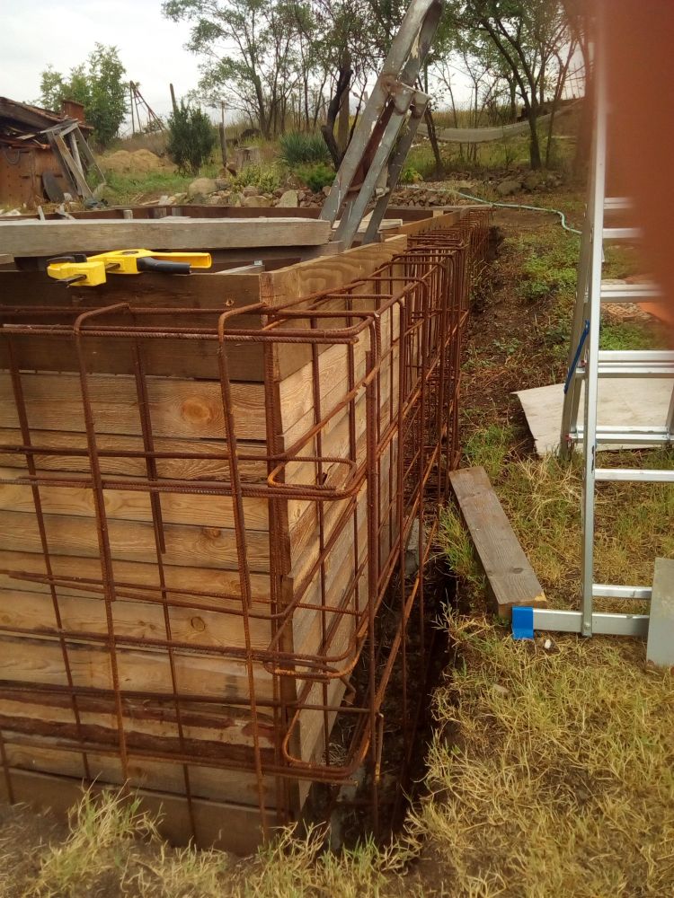 Shuttering is a former made out of planks or special wooden sheets, to use as a mould for concrete. In this photo you can also see the metal reinforcing which will be inside the concrete once it is poured.
There is then another row of shuttering built to enclosed the metal.