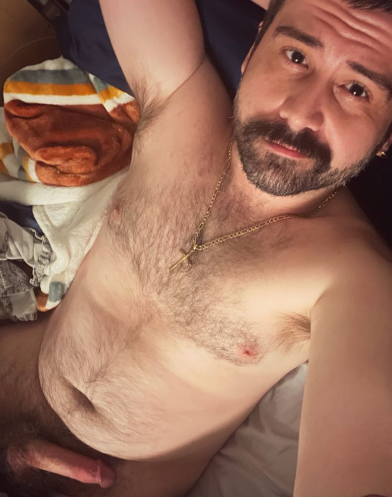Hairy man in bed - dick pointing left.