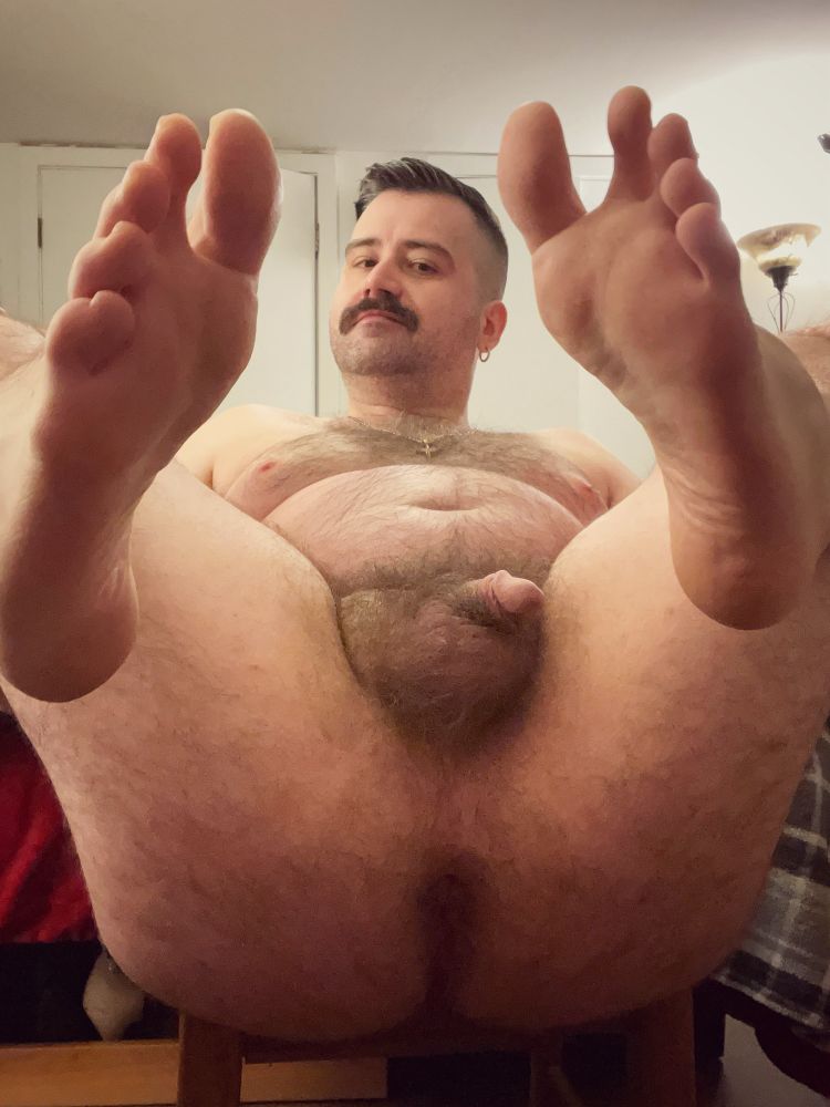 Nude hairy man with his legs back and feet forward.