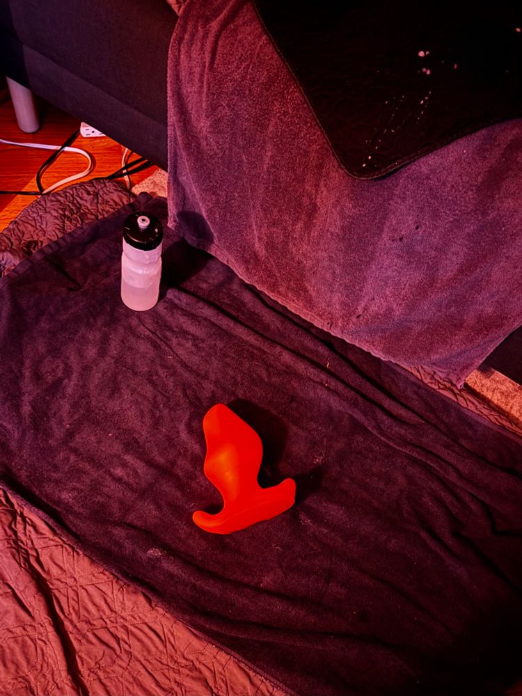 I forgot to get a picture of the butt plug in me, strapped on with a leather butt plug harness. So here’s a picture of the neon orange Snuckle after I finally pushed it out on the ground when greasy20’s hole was finally satiated. 