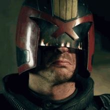 Gif of Judge Dredd watching something burn, with the flames reflecting in his helmet visor. His habitual scowl is present.