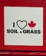 White sticker on a red background reading "I love Canadian soil and grass"