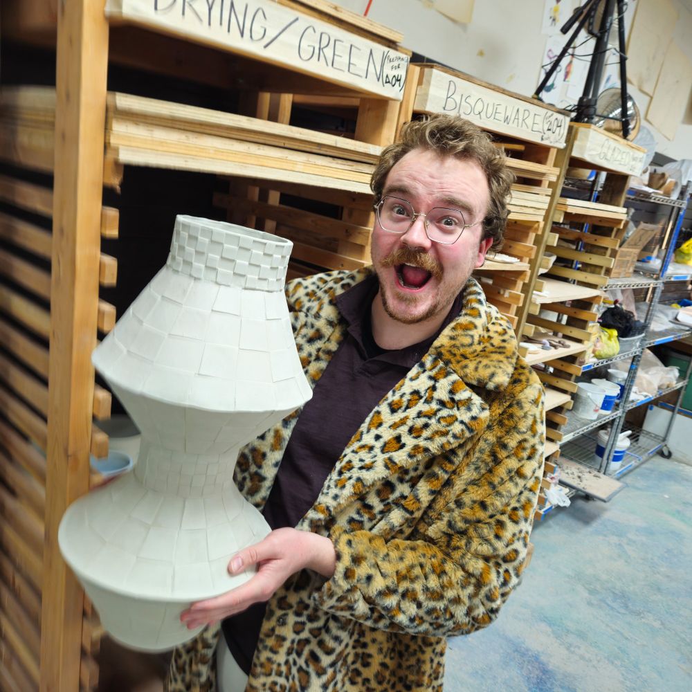 I'm wearing cheetah print faux fur coat and I am holding my 22 inch tall geometric vase. I'm smiling with my mouth open. 