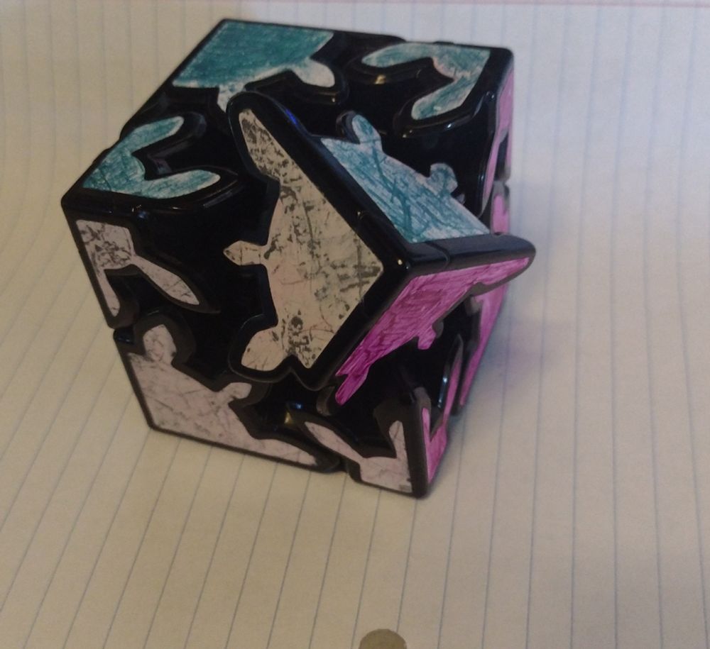 A cube puzzle, like a Rubik's Cube but the corners are gears and you rotate them around each other to scramble or unscramble the colors.

One of the gears has gotten misaligned by a tooth, so it's cranked over a little even though the entire puzzle is "solved."