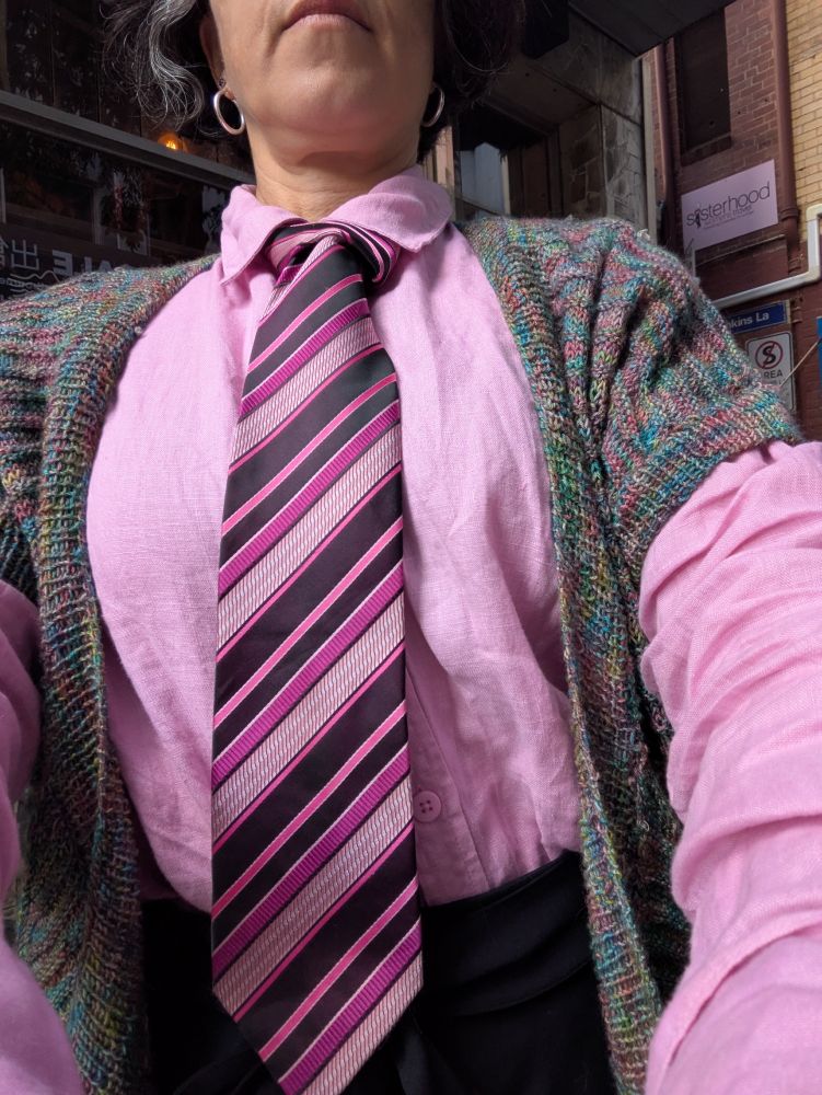 A woman wears a pink shirt with a tie as described in the text. Some of the stripes are the exact same shade of pink as the shirt.