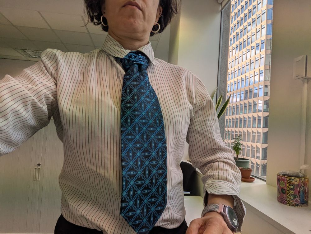 A woman wears a blue tie with a repeating pattern.