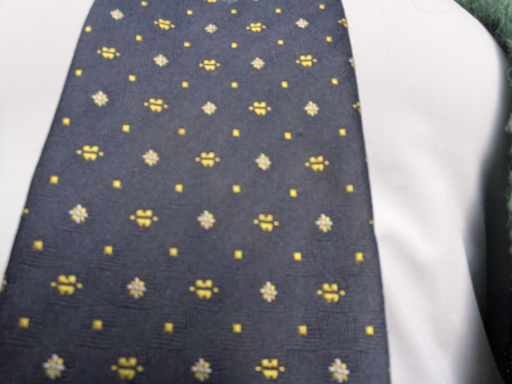 A close up of the tie. It appears to have tiny gold teeth and sunbursts on it.